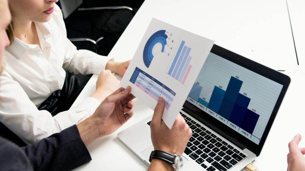 someone looking at computer screen and paper with graphs on it