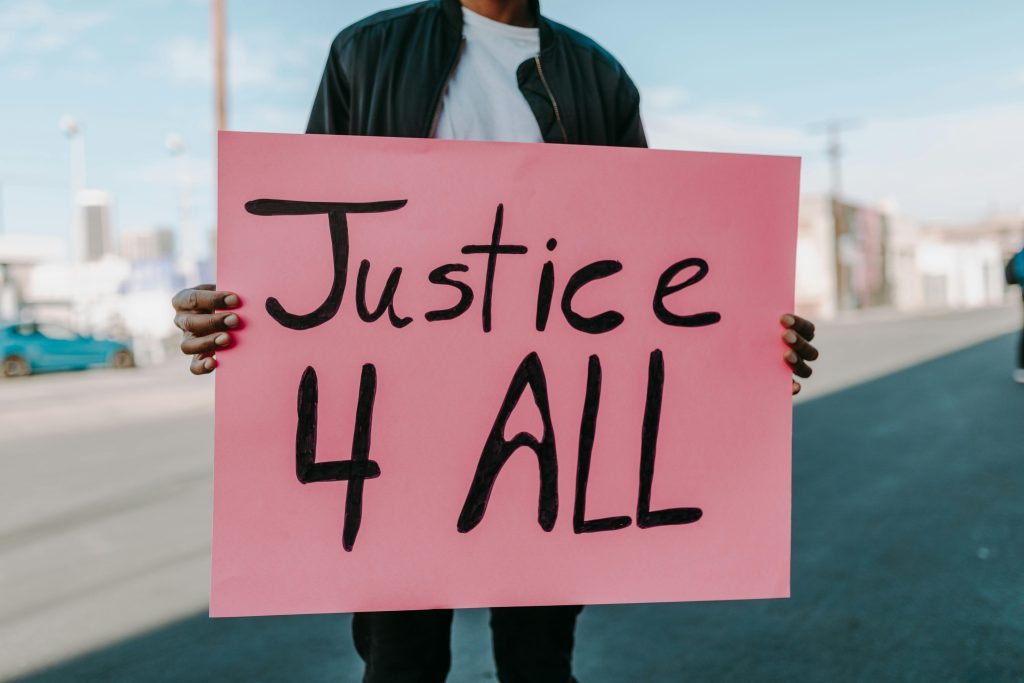 A person holding a sign that reads "Justice 4 All."