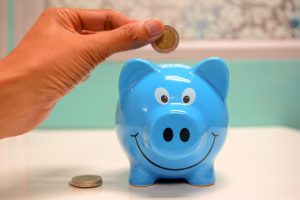coin being put in a blue piggy bank