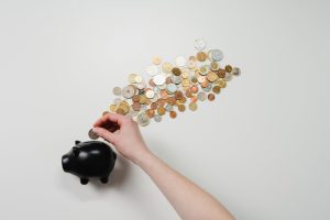 coins lining up to black piggy bank